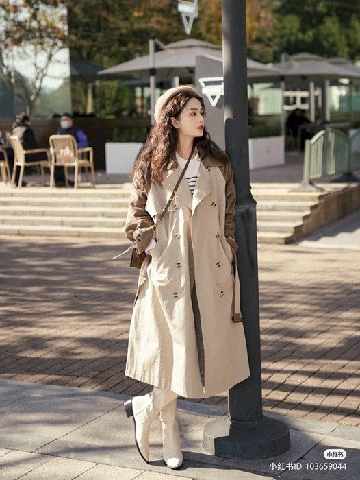 Tạo dáng đứng tựa vào một cây cột đèn trên phố, chân bắt chéo cá tính, mặt quay nghiêng nhìn về phía trước