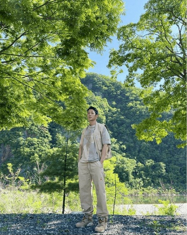 Tạo dáng đứng hơi nghiêng người hướng về ống kính máy ảnh, hai tay đút túi quần, chân đứng chữ A, mặt nhìn vào ống kính