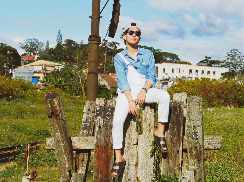 Tạo dáng ngồi trên những bục gỗ, một chân duỗi, một chân co, tay gác lên đùi, mặt hơi hướng lên về phía ống kính