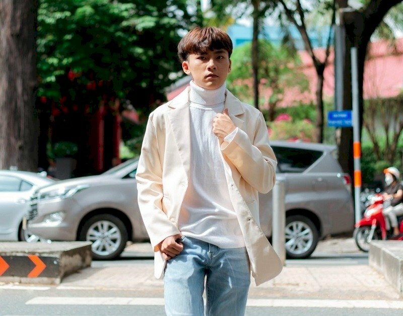 Tạo dáng tư thế bước đi, một tay đút túi quần, một tay cầm cổ áo, mắt nhìn thẳng