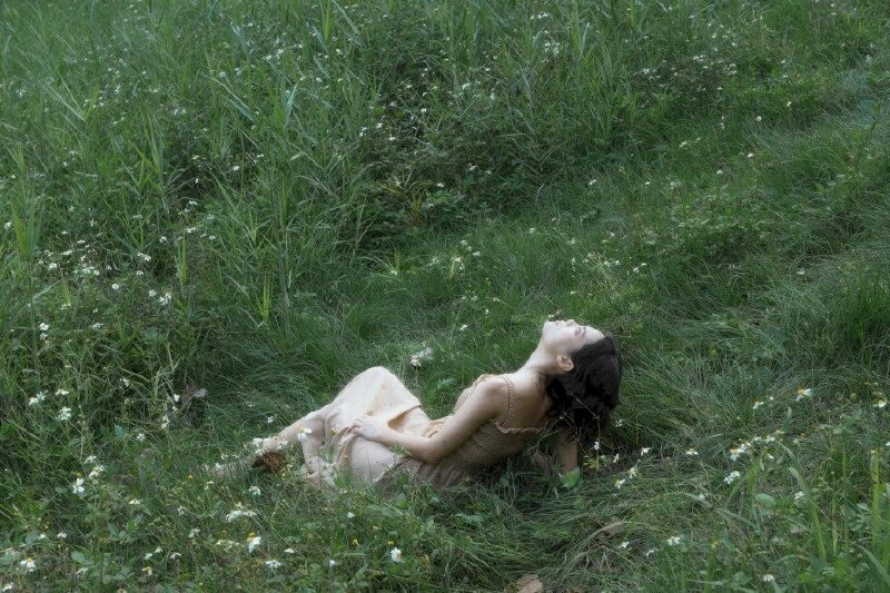 tạo dáng ngồi trên thảm cỏ nhưng không thẳng lưng mà hơi nghiêng người về sau, mặt ngưới lên nhìn trời