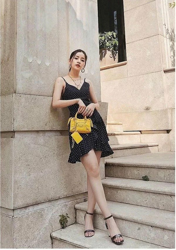 Tạo dáng chụp ngoại cảnh cùng những bậc thang với tư thế đứng tựa vào tường, hai chân bắt chéo, hay tay cầm túi ngang ngực