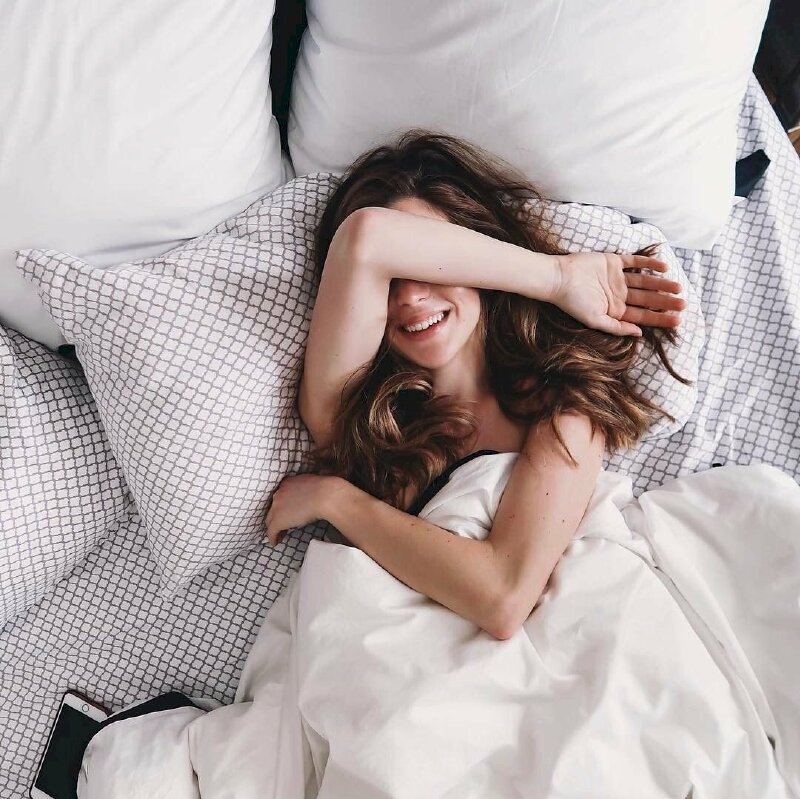 Kiểu tạo dáng đơn giản nằm trên giường như vừa mới ngủ dậy với một tay khoanh để lên ngực, một tay đặt ngang che mắt, nụ cười tươi
