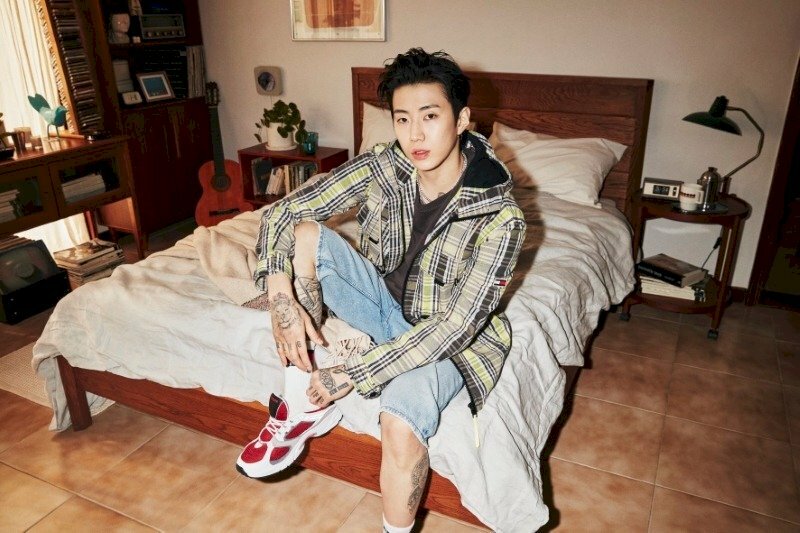 Tạo dáng ngồi trên giường chống chân, mắt nhìn hướng thẳng máy ảnh