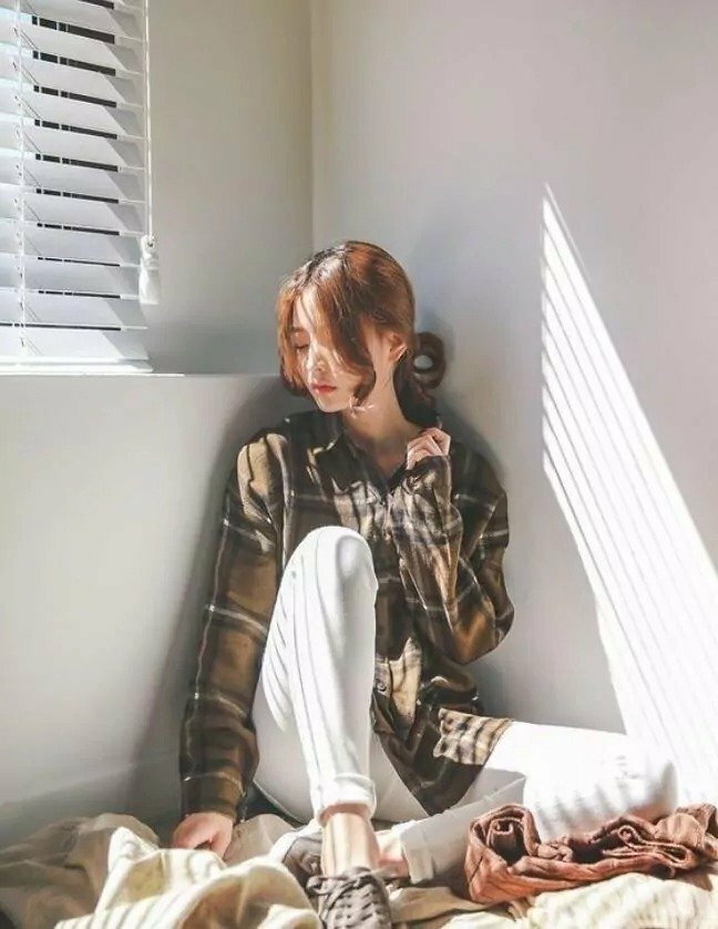 Tạo dáng ngồi tựa lưng vào tường, một chân co gối, một chân xếp ngang, một tay thả tự nhiên, một tay co đưa lên khẽ chạm cổ, mặt quay nghiêng hơi cúi