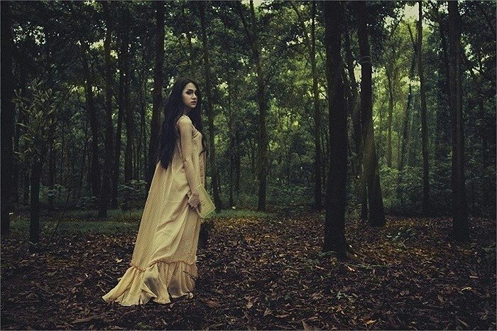 Tạo dáng như quay lưng bước đi vào trong rừng với mặt quay lại hướng ánh mắt nhìn máy ảnh một cách xa xăm mơ hồ