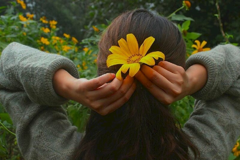 Tạo dáng nhẹ nhàng với hai tay đưa ra sau cài hoa dã quỳ lên tóc