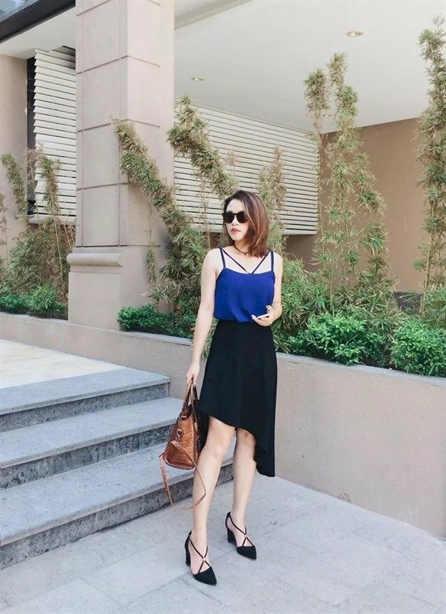 Tạo dáng chân đứng hình chữ A, mặt quay nghiêng, cầm túi ở tay