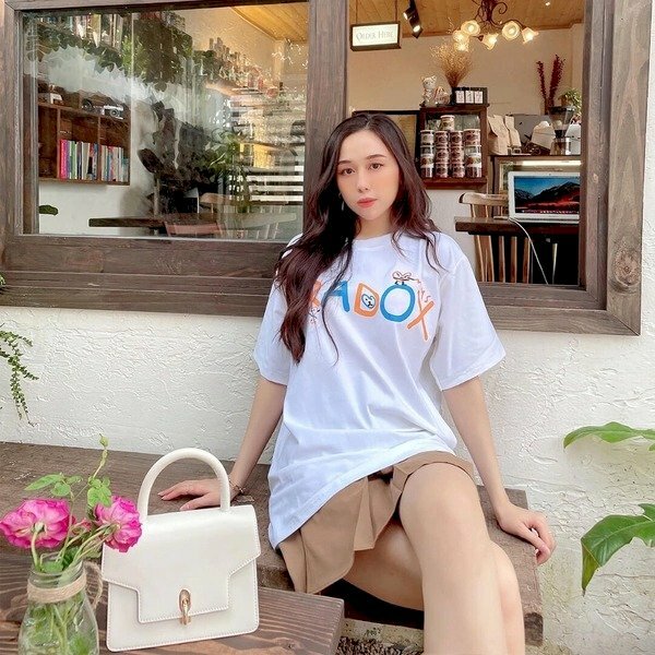 Tạo dáng ngồi tựa lưng với hai tay chống hai bên, hai chân bắt chéo, đầu nghiêng nhẹ với mắt nhìn thẳng ống kính