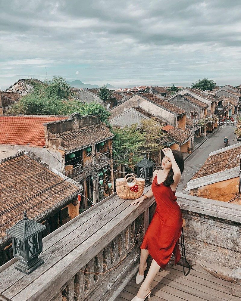 Tạo dáng tư thế ngồi với phần trên hơi ưỡn về trước, một chân co nhẹ, một chân duỗi tự nhiên, một tay giơ lên để nhẹ nhàng ngang trái, mặt hướng cằm lên với mắt nhắm hờ, chiếc túi xinh xắn đặt bên cạnh