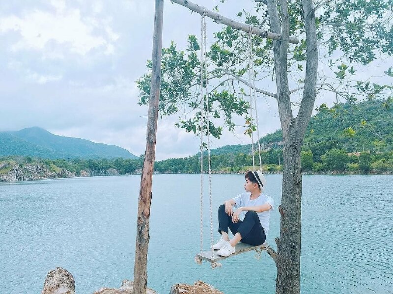 Tạo dáng ngồi co 02 chân trên xích đu, hai tay gác trên đầu gối, mặt quay nghiêng hướng ánh mắt nhìn về xa xăm