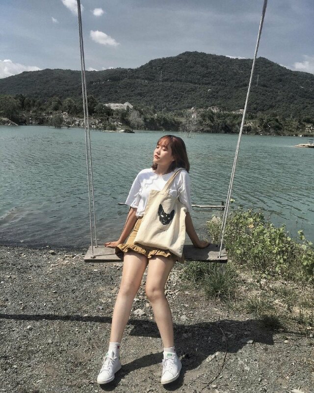 Tạo dáng ngồi hơi ngả người về sau, hai tay chống lên xích đu, hai chân duỗi tự nhiên, mặt khẽ hướng cằm lên trên