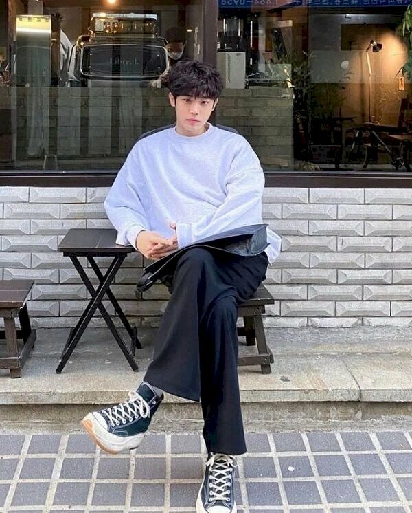 tư thế tạo dáng ngồi vắt chân, hơi nghiêng người với một tay tựa lên bàn