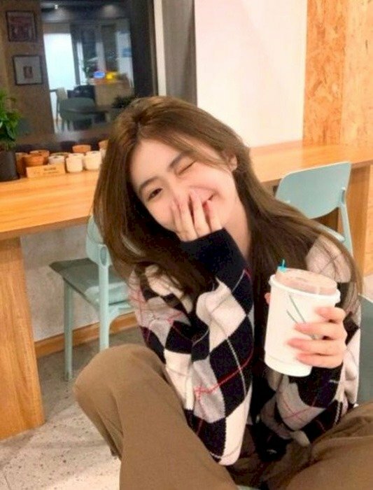 Kiểu tạo dáng ngồi trên ghế, hai chân co lên, đầu nghẽ nghiêng, tay che miệng cười duyên