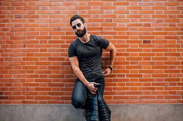 Tạo dáng hơi dựa lưng vào tường, một chân chống lên tường