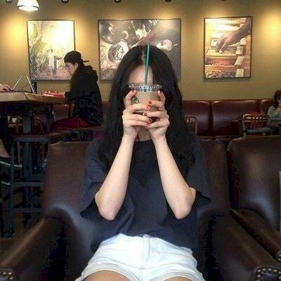 Tạo dáng kiểu ngồi thật tự nhiên, dựa người vào ghế, hai tay cầm ly trà sữa che mặt