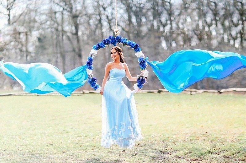 Tạo dáng ngồi trên xích đu đung đưa nhẹ nhàng, mặt quay nghiêng với nụ cười toả nắng