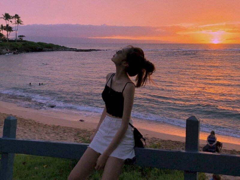 Tạo dáng ngồi nghiêng trên thành bờ rào, mặt hướng nhìn lên trên