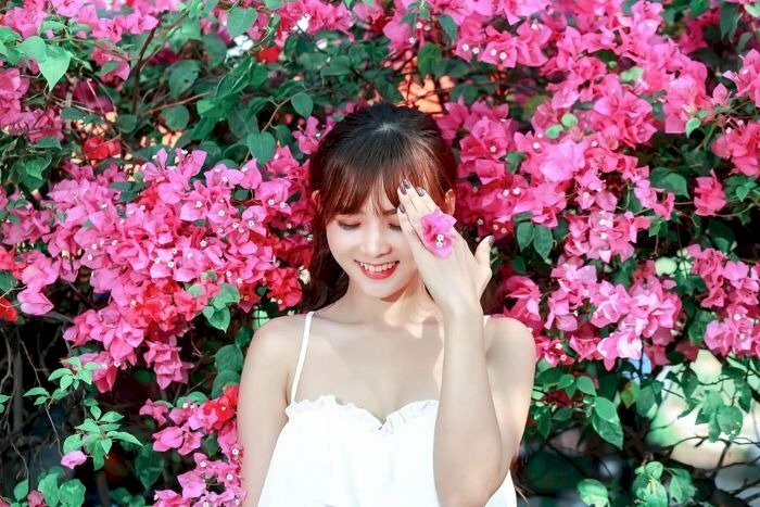 Tạo dáng nhẹ nhàng lấy tay như che nắng, hơi cúi nhẹ nhìn xuống, miệng cười thật duyên