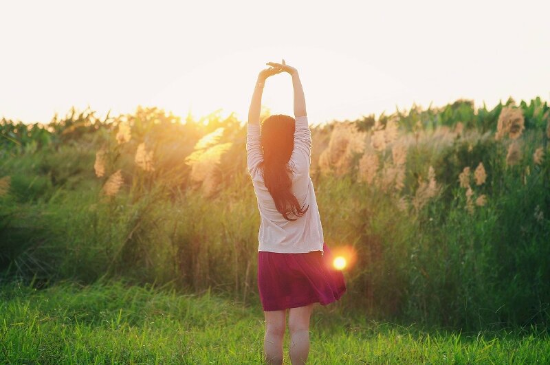 Tạo dáng đứng thẳng giơ cao hai tay qua đầu, hai bàn tay đan nhẹ vào nhau