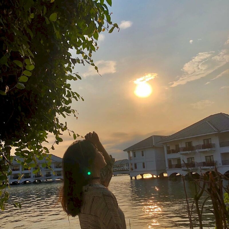 Góc chụp nghiêng, mặt hơi hướng cằm lên, tay nhẹ đưa lên vuốt tóc