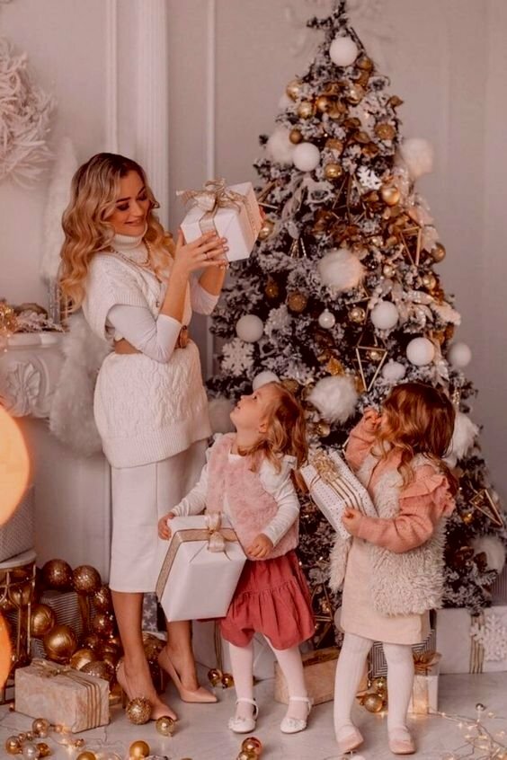 Tạo dáng ba mẹ con chụp ảnh bên cây thông mừng Giáng sinh, với ánh mắt mẹ nhìn hai con và hai cô con gái nhỏ ngước nhìn mẹ