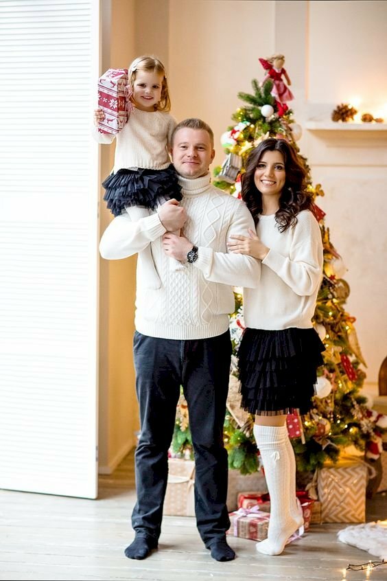 Tạo dáng chụp ảnh gia đình mùa Giáng sinh, tay bố nâng con ngồi trên vai, vợ đứng cạnh chồng miệng cười tươi