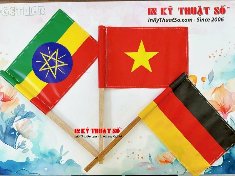 In cờ cầm tay vải Silk cắt hình chữ nhật, may 4 cạnh như lá cờ, gắn thanh gỗ tròn phi nhỏ cao 30cm