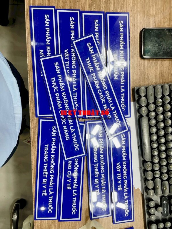 In bảng tên kệ tủ nhà thuốc Sản phẩm không phải là... , in UV thuận Mica xanh 5li cắt hình chữ nhật - INKTS3345